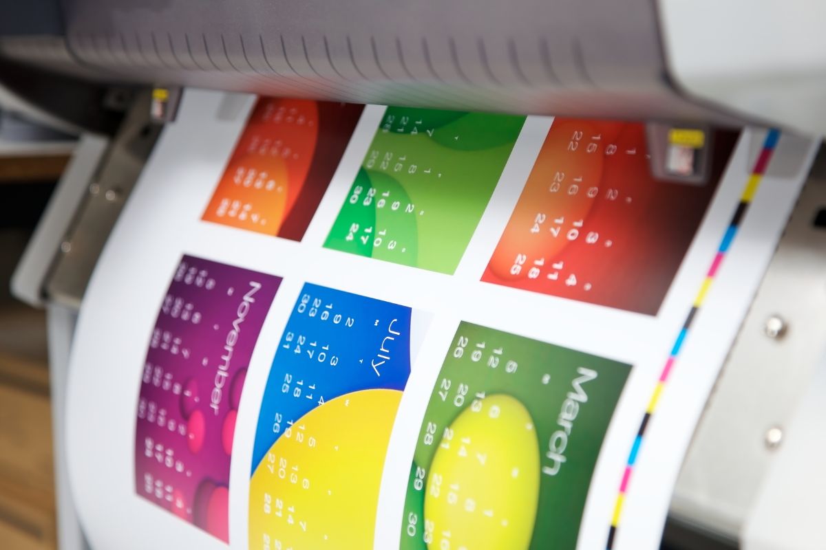 A calendar being printed under a printing machine.