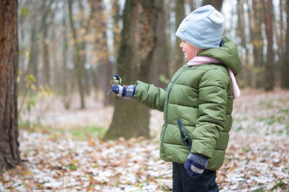 A kid wearing puffer jacket while playing outside.