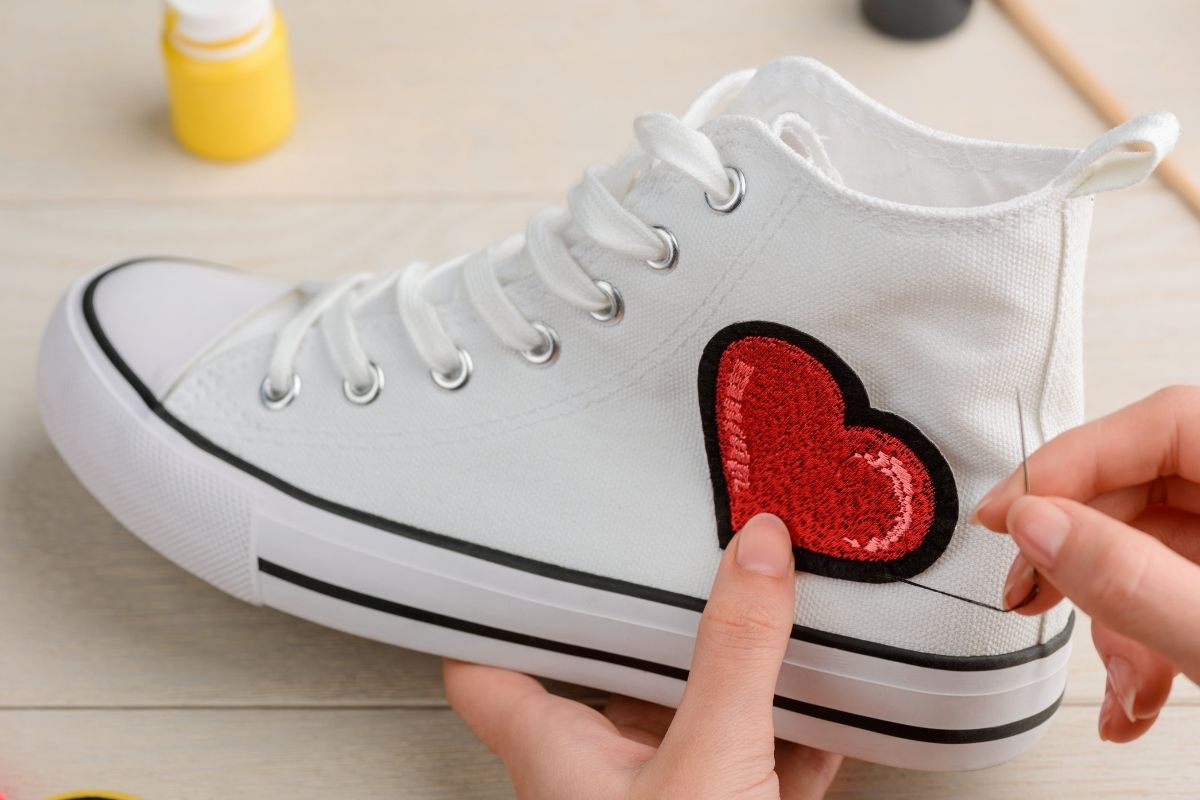 A lady doing patch embroidery on her shoe.