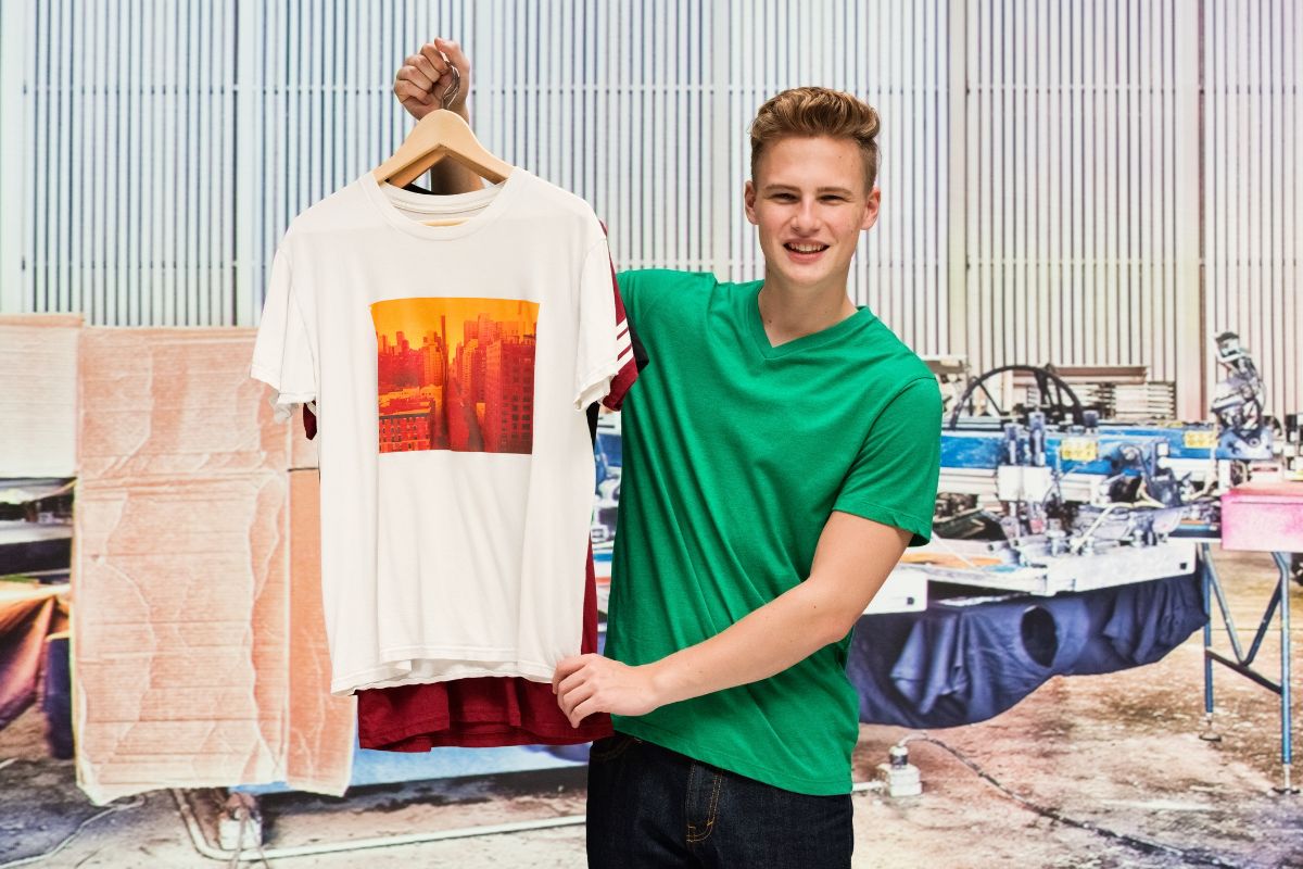 A man showing his print on demand t-shirt in his workshop.