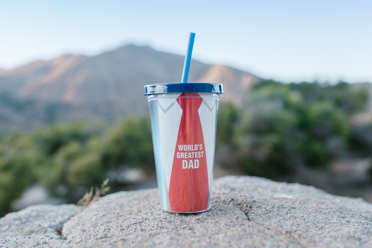 A tumbler kept on a rock with customized prints on it.