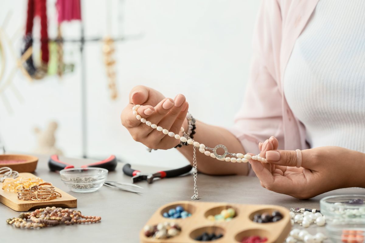 A woman enhancing her jewelry with personalized touches to make it more appealing.