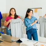 Two girls holding t shirts showing the difference between dropshipping and print on demand