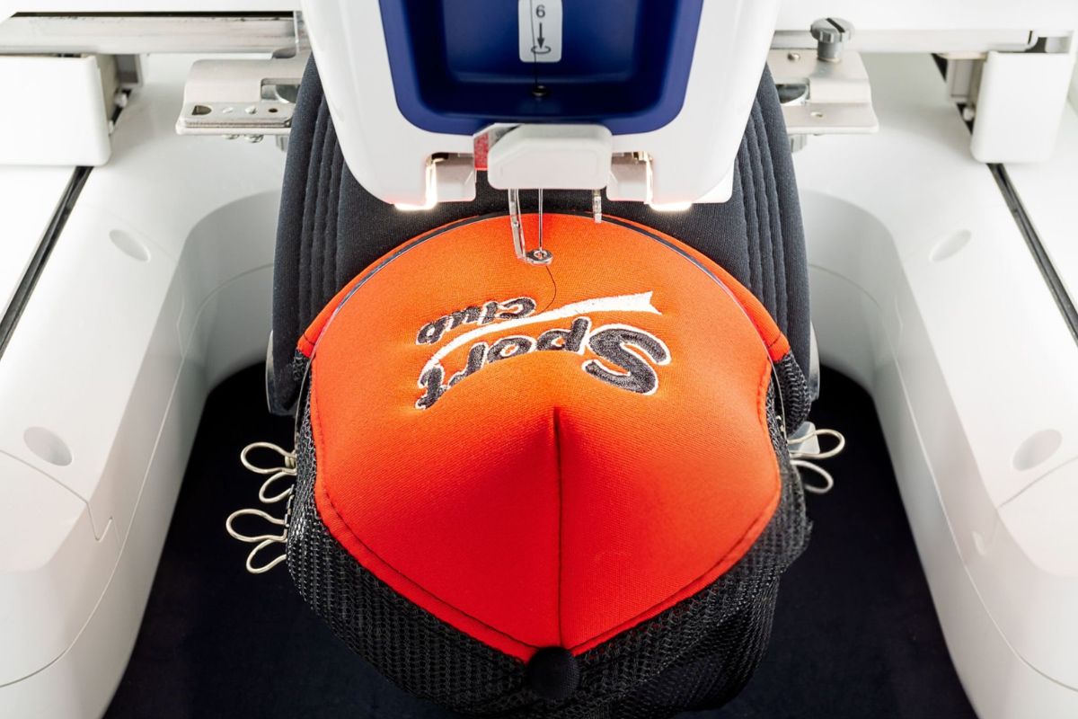 A hat is being embroidered with its logo by a machine