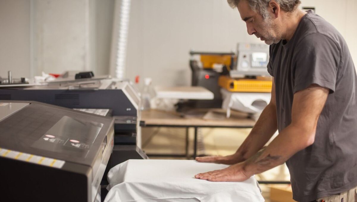 A person doing custom T-Shirt Printing on a machine