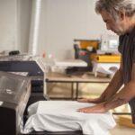 A person doing custom T-Shirt Printing on a machine