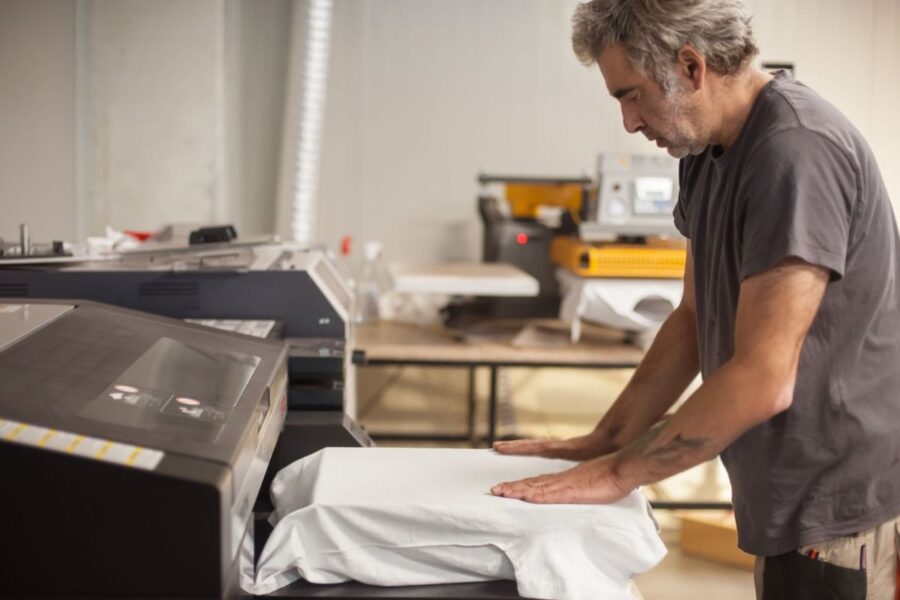 A person doing custom T-Shirt Printing on a machine