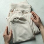 A person folding custom printed sweatpants