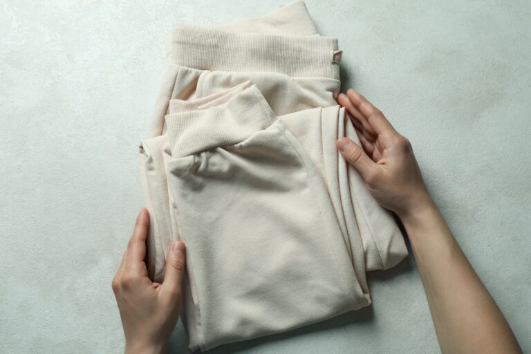 A person folding custom printed sweatpants