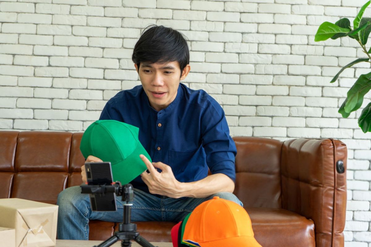 A person is selling different types of hats using a social media app on his phone