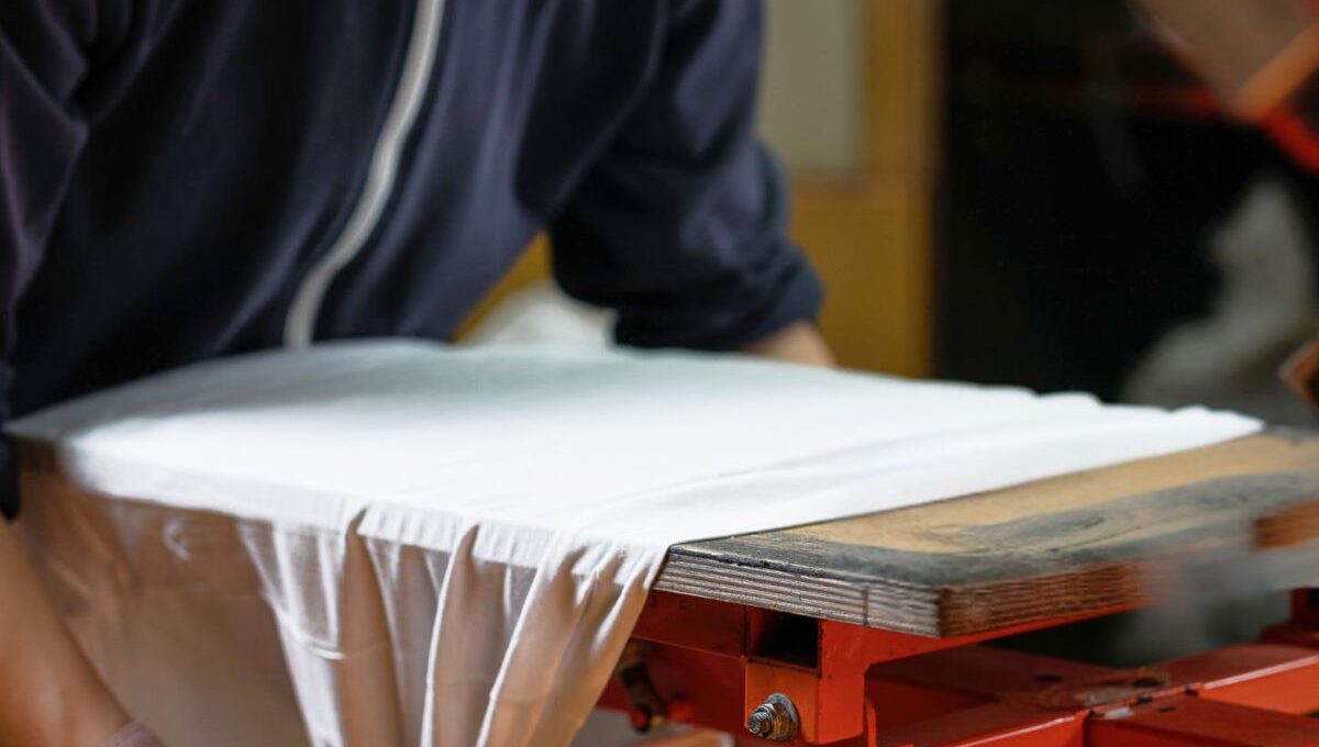 A person printing custom design on sleeveless T-Shirts