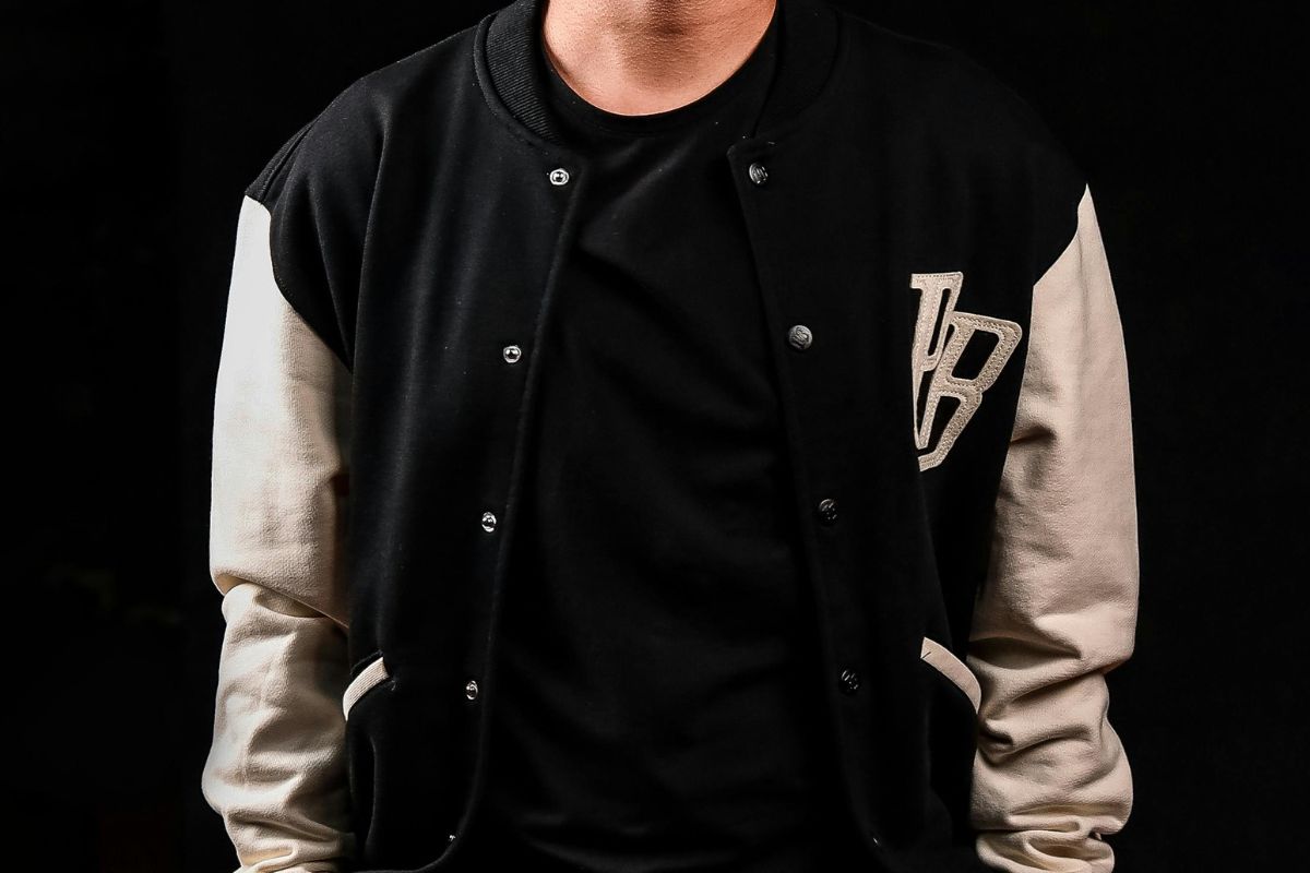 A person wearing an embroidered varsity jacket with his name initials on it