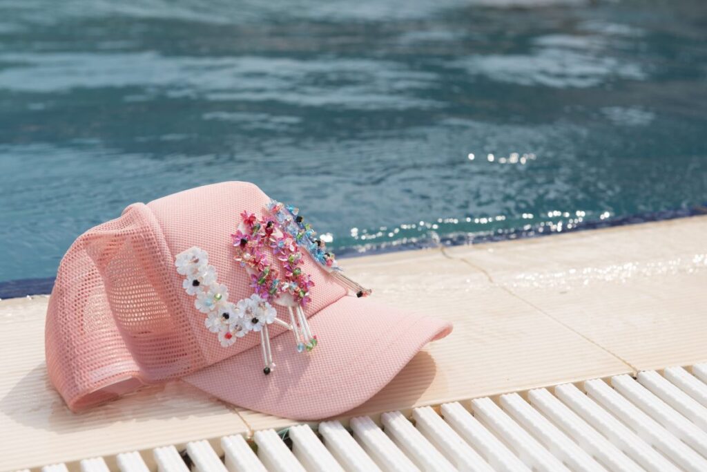 A woman's custom trucker cap placed beside the swimming pool