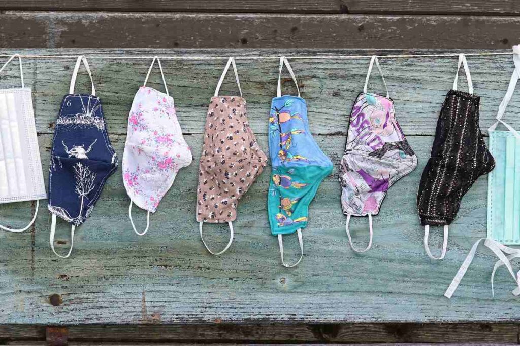 A collection of different custom-printed face masks is being dried outside