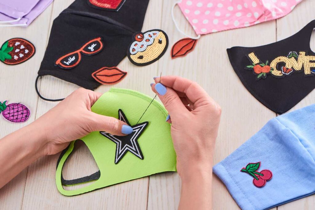 A lady sewing embroidered patches to face masks