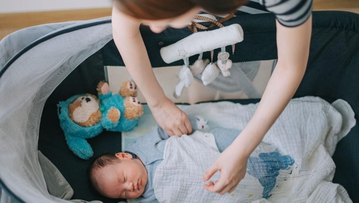 A mother gently covering her baby with a personalized blanket