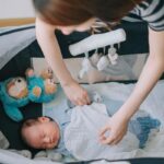 A mother gently covering her baby with a personalized blanket