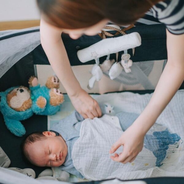 A mother gently covering her baby with a personalized blanket