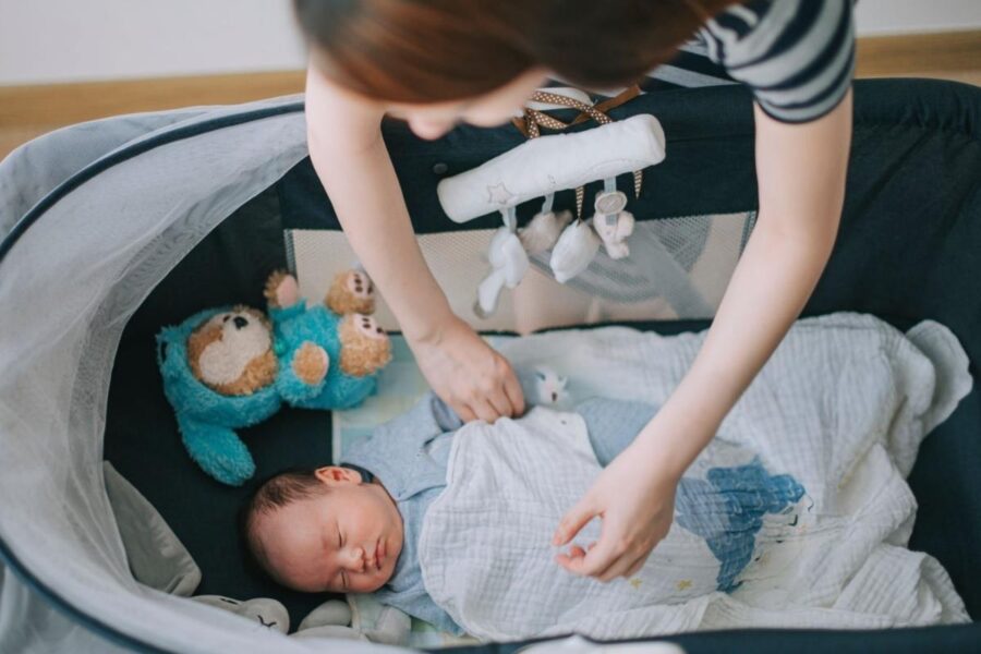A mother gently covering her baby with a personalized blanket