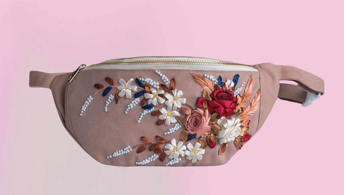 An embroidered fanny pack with some flowers embroidered on it.
