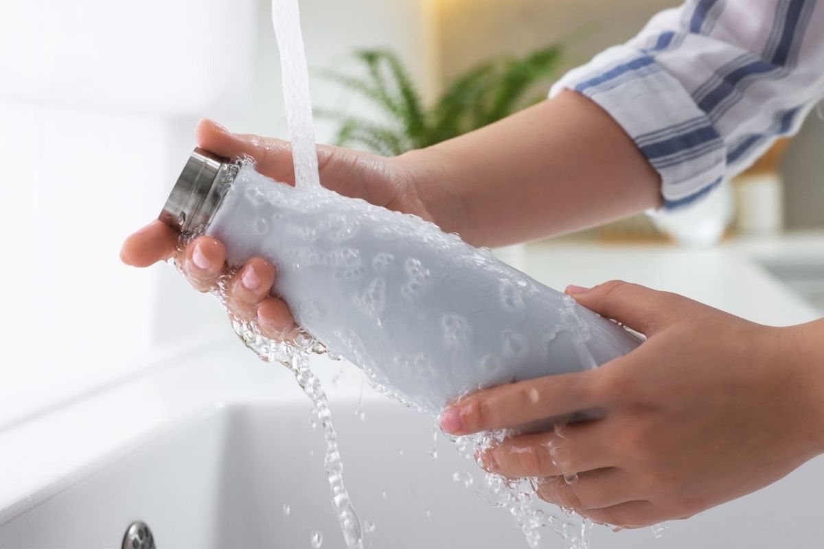 A person cleaning stainless steel water bottle