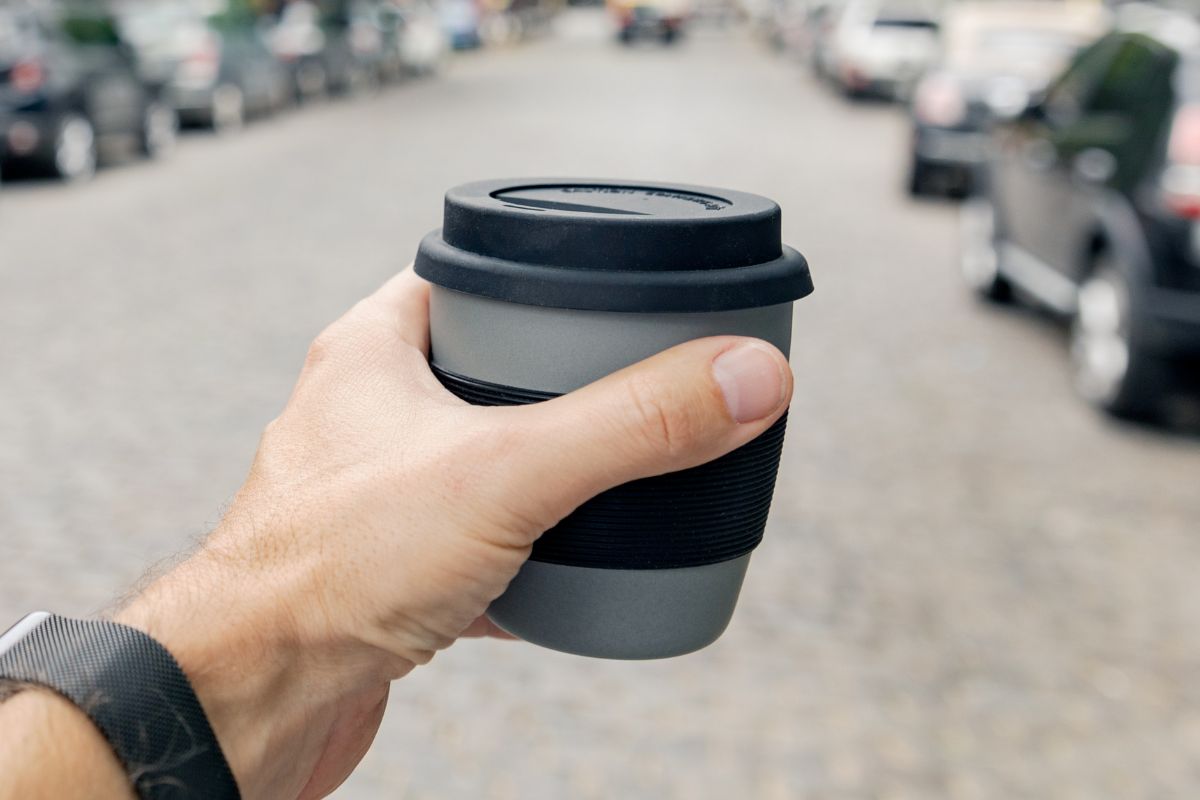 A person holding a travel mug