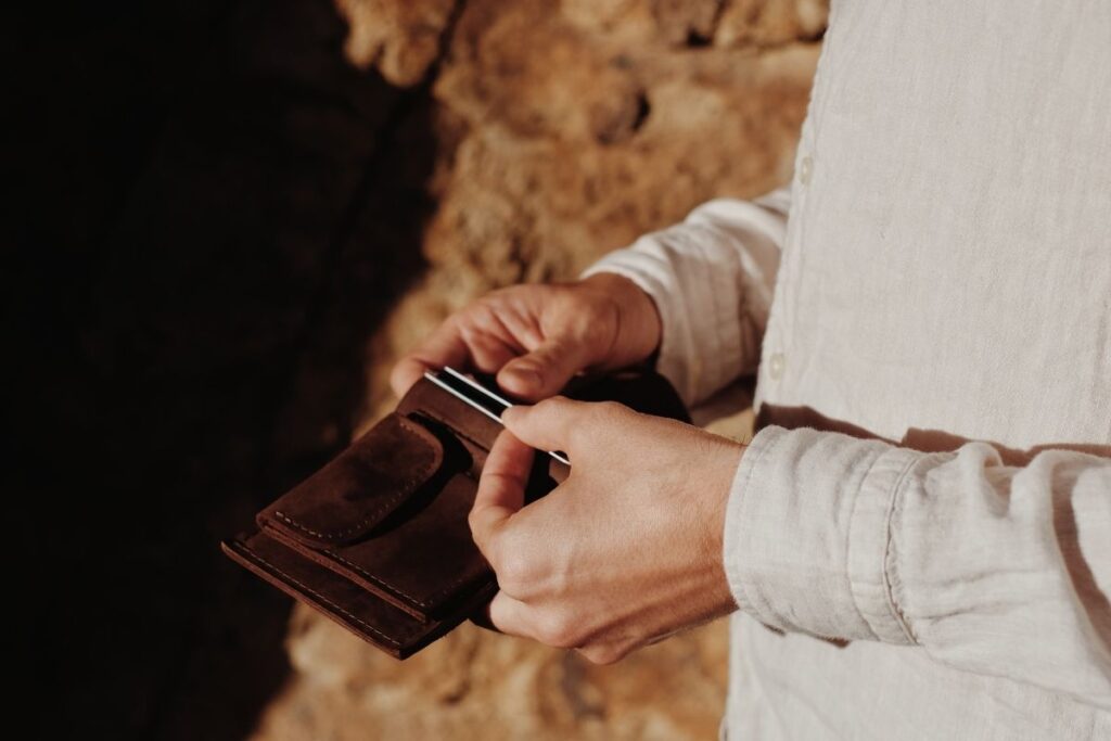 A person is showing a leather wallet and the personal items kept inside it